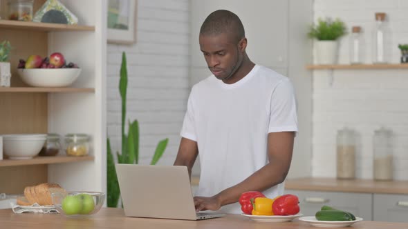 Athletic African Man Working on Laptop in Kitchen