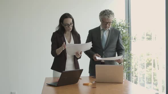 Serious Male Boss Giving Documents To Assistant