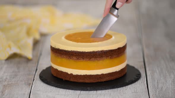 Cutting Homemade Chocolate Sponge Cake with Peach Mousse and Jelly