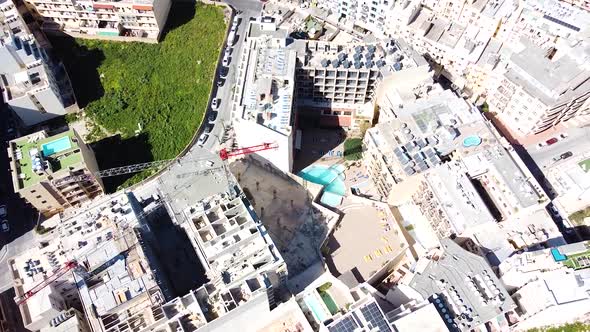 St Paul Bay downtown with hotel buildings and construction cranes. Aerial tilt up view reveal blue o