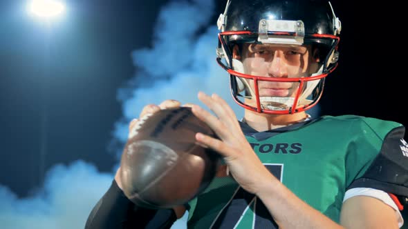 American Football Player Poses with a Ball in Hands, Close Up.