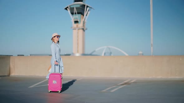 Slow Motion Stylish Traveler Female with Airport Airport Tower on Background