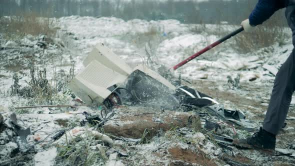 One Person Smashes Old TV at a Dump, Using Hammer.