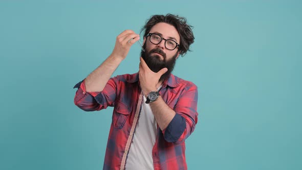 A Bearded Man Applies His Beard Care Oil, Isolated on a Turquoise Background