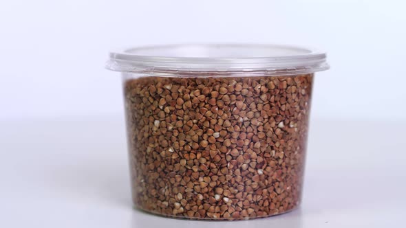 Close-up, Buckwheat Into Plastic Packaging, Box, Rotates on White Background. Grocery Online