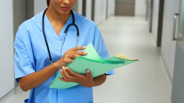 Smiling doctor with medical report standing in corridor