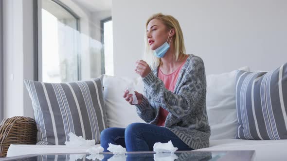 Sick woman holding tissues sitting on the couch at home