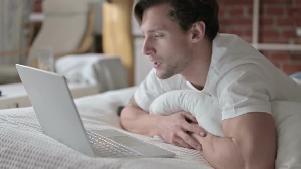 Ambitious Young Man Doing Video Chat on Laptop in Bed