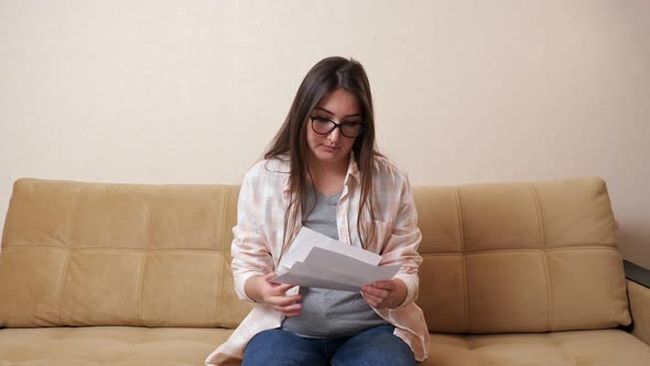 Woman Opens Envelope with Bill and Becomes Nervous on Couch