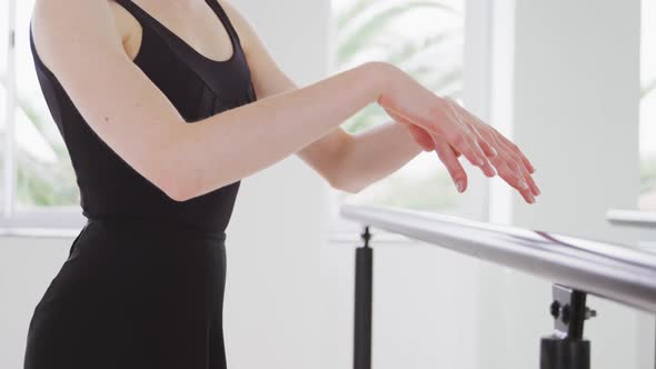 Caucasian female ballet dancer practicing up by the mirror for dance class in a bright studio