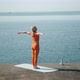 A Woman on the Seashore Practices Yoga Pulls Her Hands to the Sun Harmony - VideoHive Item for Sale