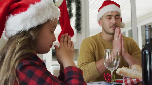Focused caucasian daughter and father praying together before christmas dinner