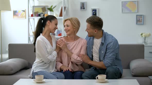 Young Couple and Mother in Law Holding Hands, Smiling at Camera, Happy Together