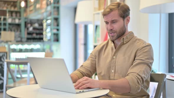 Video Chat on Laptop By Young Man in Cafe