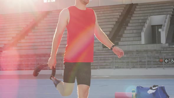 Midsection of caucasian disabled male athlete with running blade stretching