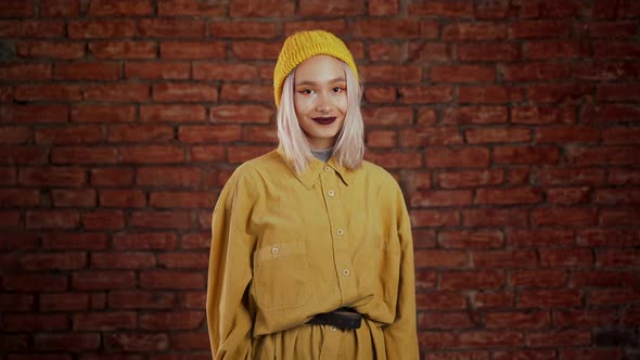 Young Woman in Yellow Look. Portrait of Flirting Beautiful Girl on Bricks Wall