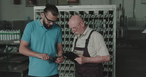 The Manager Measures Detail with Calipers and Engineer Noting Data on a Tablet