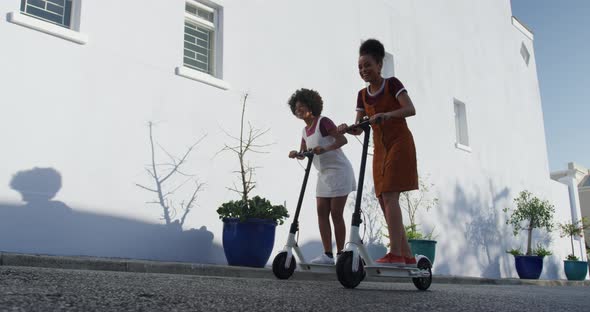 Two mixed race women riding electric scooter