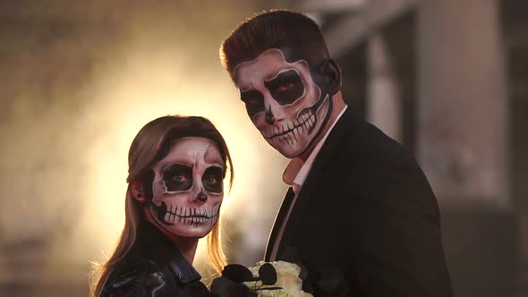 Couple with Dark Skull Makeup on the Background of Burning Fire and Smoke