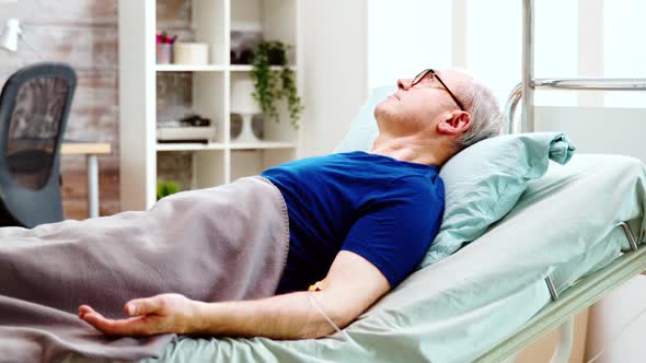 Portrait of Elderly Sick Man Lying in Hospital Bed