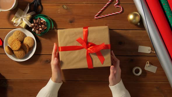 Hands with Wrapped Christmas Gift on Wooden Table