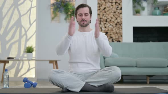 Portrait of Young Man Meditating on Yoga Mat at Home