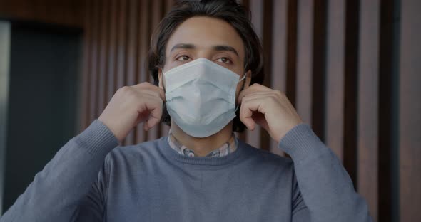 Slow Motion Portrait of Arab Guy Taking Off Medical Face Mask and Breathing Hard Indoors