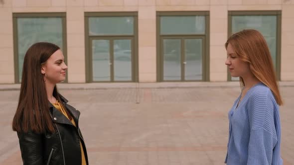 Two Cheerful Girls Elbows Instead of Shaking Hands in the City at a Meeting