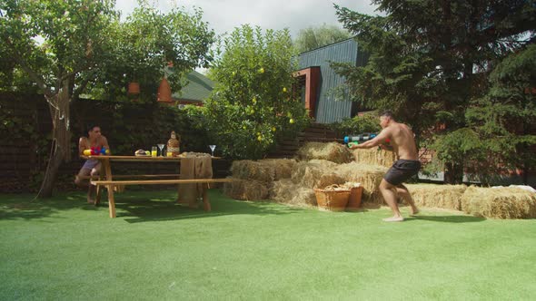 Cheerful Guys Having Water Guns Battle in Backyard