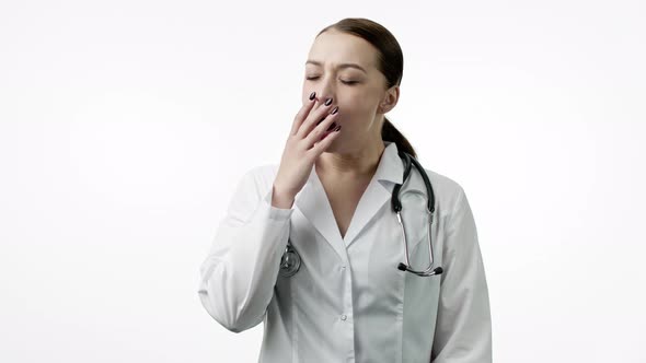 Tired Doctor Yawns, Put on Portable Neck Pillow for Nap or Snooze, Closes Eyes