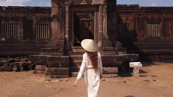 Woman in vietnamese hat go to ancient palace, Wat Phou ruined Hindu Temple. Culture Champasak, Laos