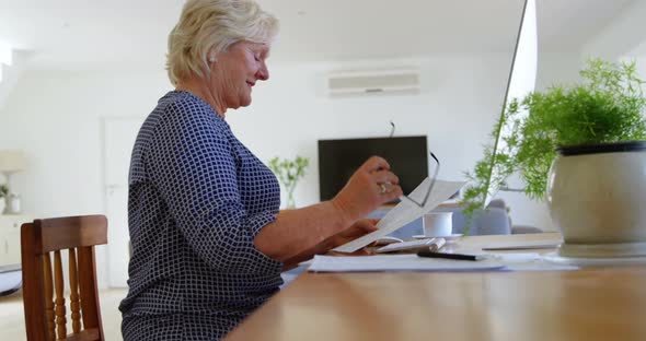 Senior woman looking at document in home 4k