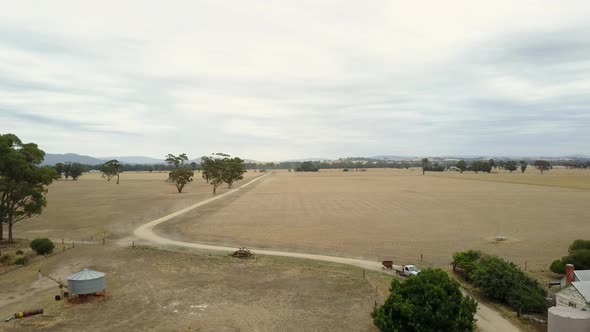 Aerial footage of farm truck driving on country road, heading for nearby farm yard.