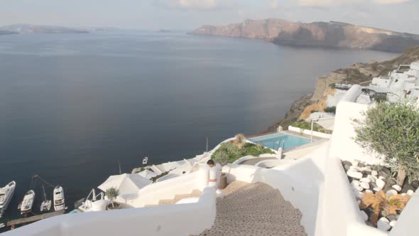 A man is rushing down some open air stairs in a village alley at the Greek village of Oia in Santori