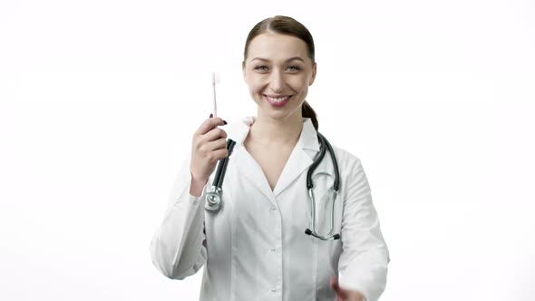 Smiling Sexy Doctor Holds Toothbrush and Shows Like Sign with Thumb Up