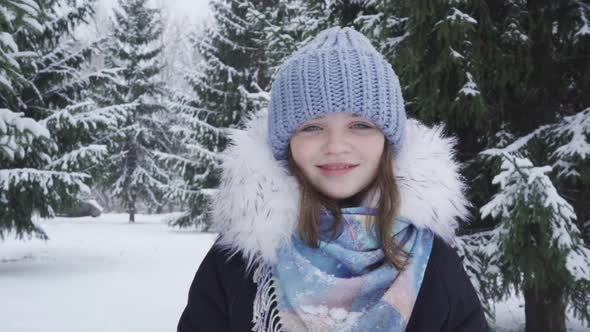 Portrait of a Happy Blueeyed Teenage Girl in a Snowy Park