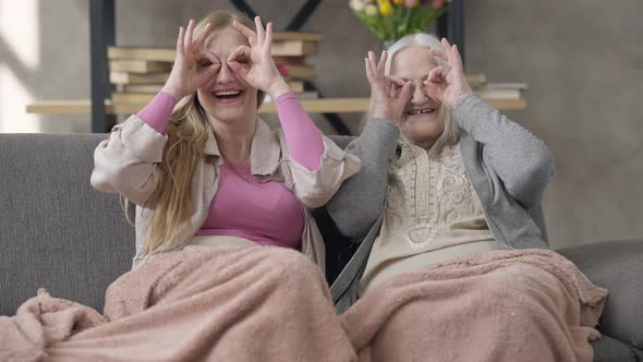 Front View Portrait of Two Relaxed Cheerful Senior Women Laughing Looking at Camera Holding Hands at