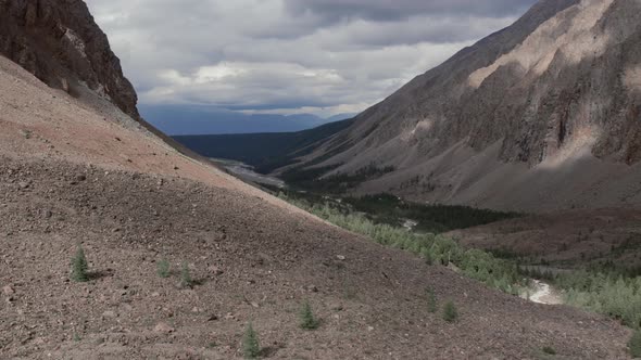 Mountains of Aktru valley with river and forest under white clouds in Altai