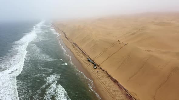 up down aerial shot of cars on a beach at the edge of the Namibia desert