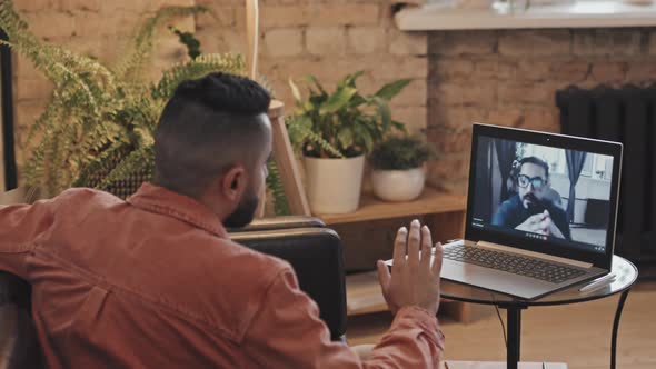 Man Discussing Project with Colleague on Video Call on Laptop