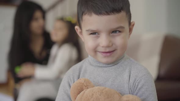 Close-up Face of a Charming Middle Eastern Grey-eyed Boy with Dark Hair Holding the Teddy Bear