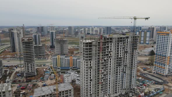 Flight Over The Construction Site. High Rise Buildings Under Construction And Construction Cranes