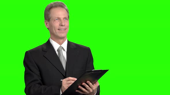 Smiling Mature Man Writing Down on Clipboard.