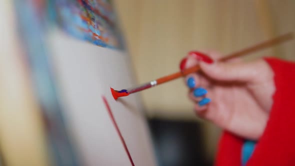 close up of woman with colorful long nails painting art on canvas