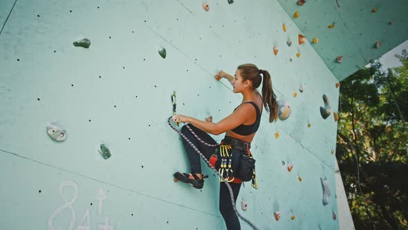 Active Woman Practicing Rock Climbing on Artificial Rock Wall in Climbing Gym Below View