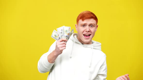 Excited Redhead Caucasian Man Bragging Dollars Posing at Yellow Background