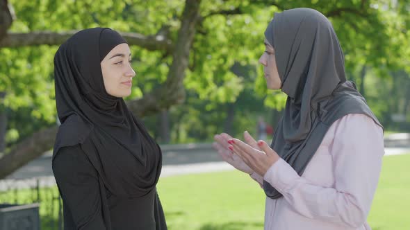 Side View of Two Emotional Muslim Women Quarrelling Outdoors. Portrait of Argued Female Friends