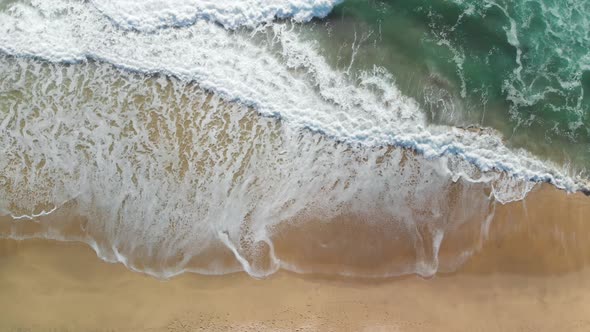 Top-down aerial shot of the blue ocean waves crashing on the California shore near Montara.