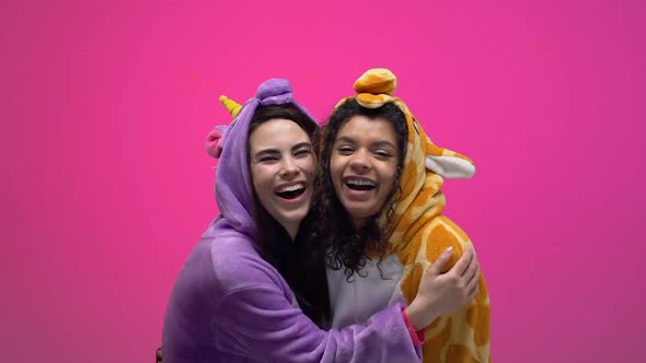 Two Women in Unicorn and Giraffe Pajamas Laughing and Hugging