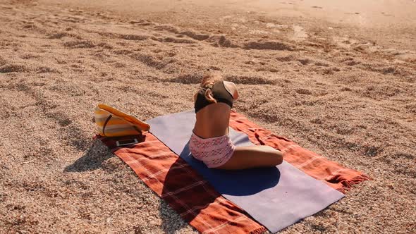 Woman is Practicing in Yoga Stretching on Mat on Seashore